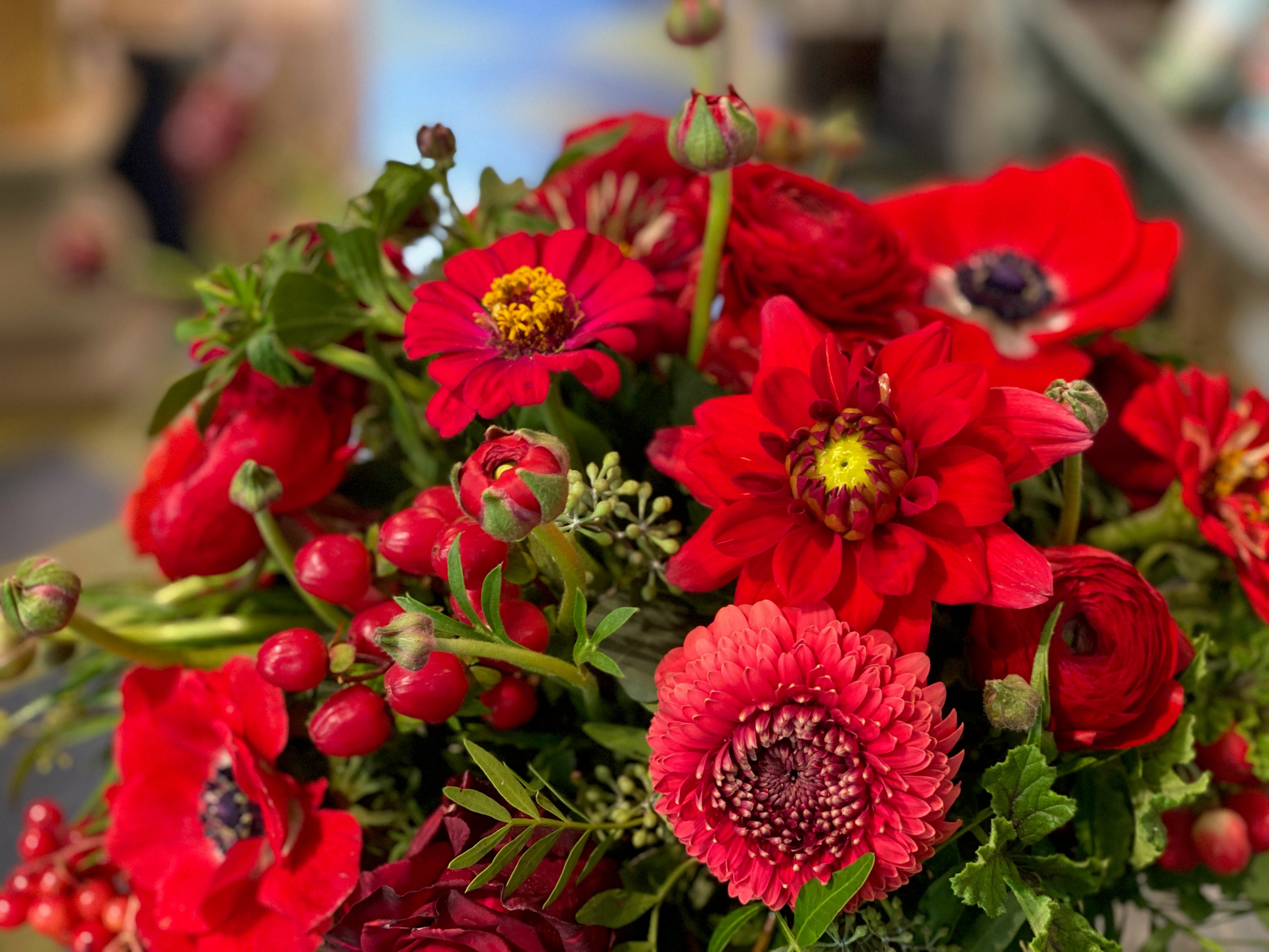 Bouquet of red flowers with green leaves on a blurred background