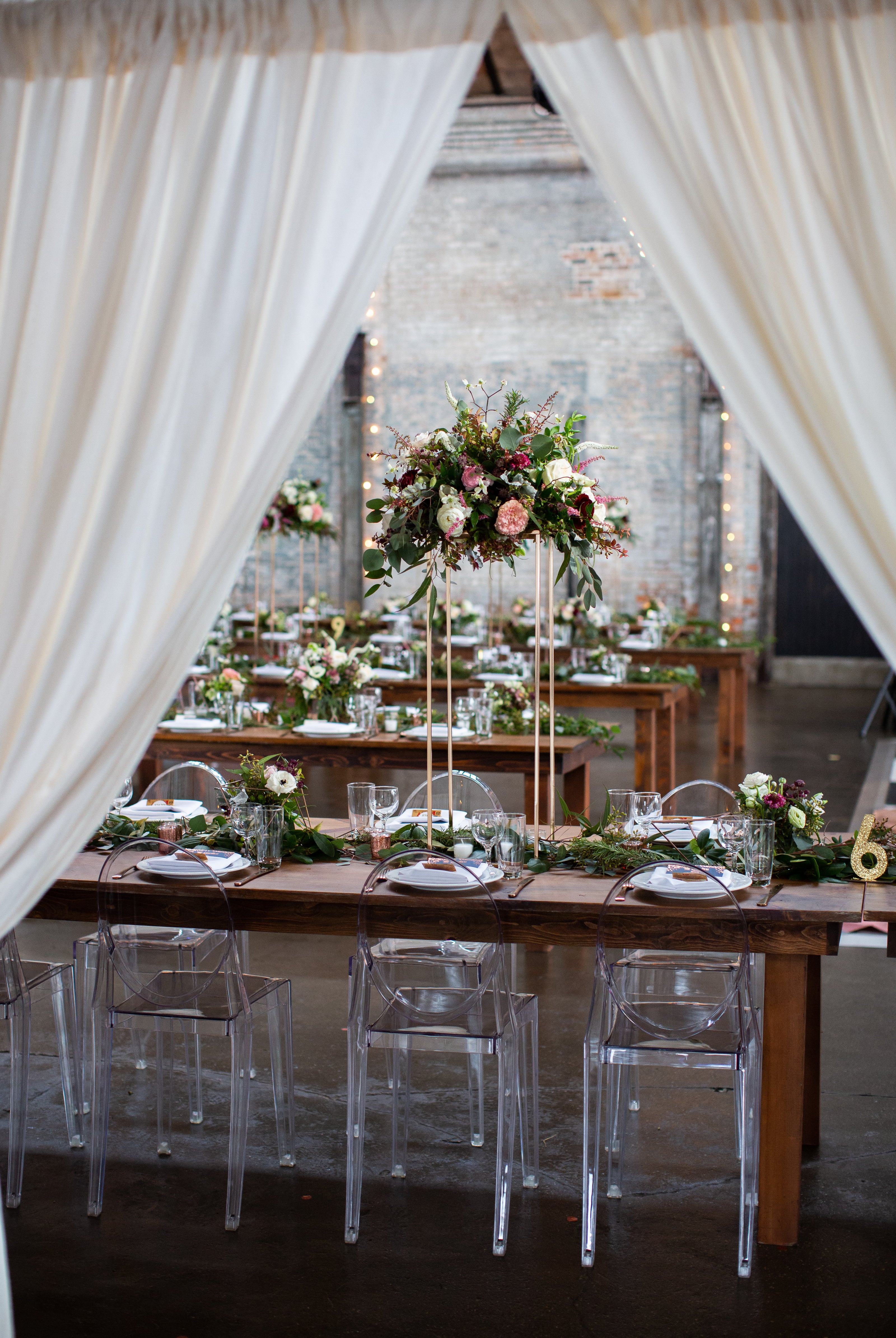 Elegant wedding reception setup with tables, chairs, and floral arrangements.